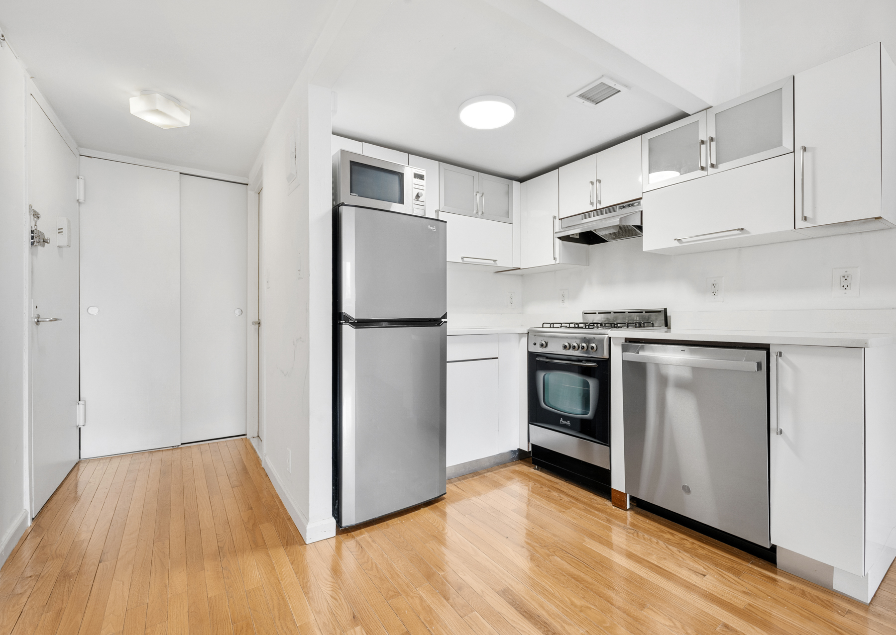 184 Thompson Street, Unit 4U Manhattan, NY 10012 - Photo 8 of 9 a kitchen with white cabinets and stainless steel appliances