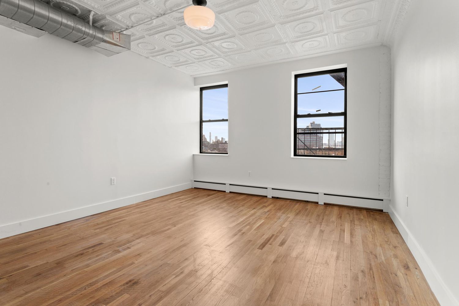 717 Manhattan Avenue, Unit 2A Brooklyn, NY 11222 - Photo 13 of 17 an empty room with wooden floor and windows