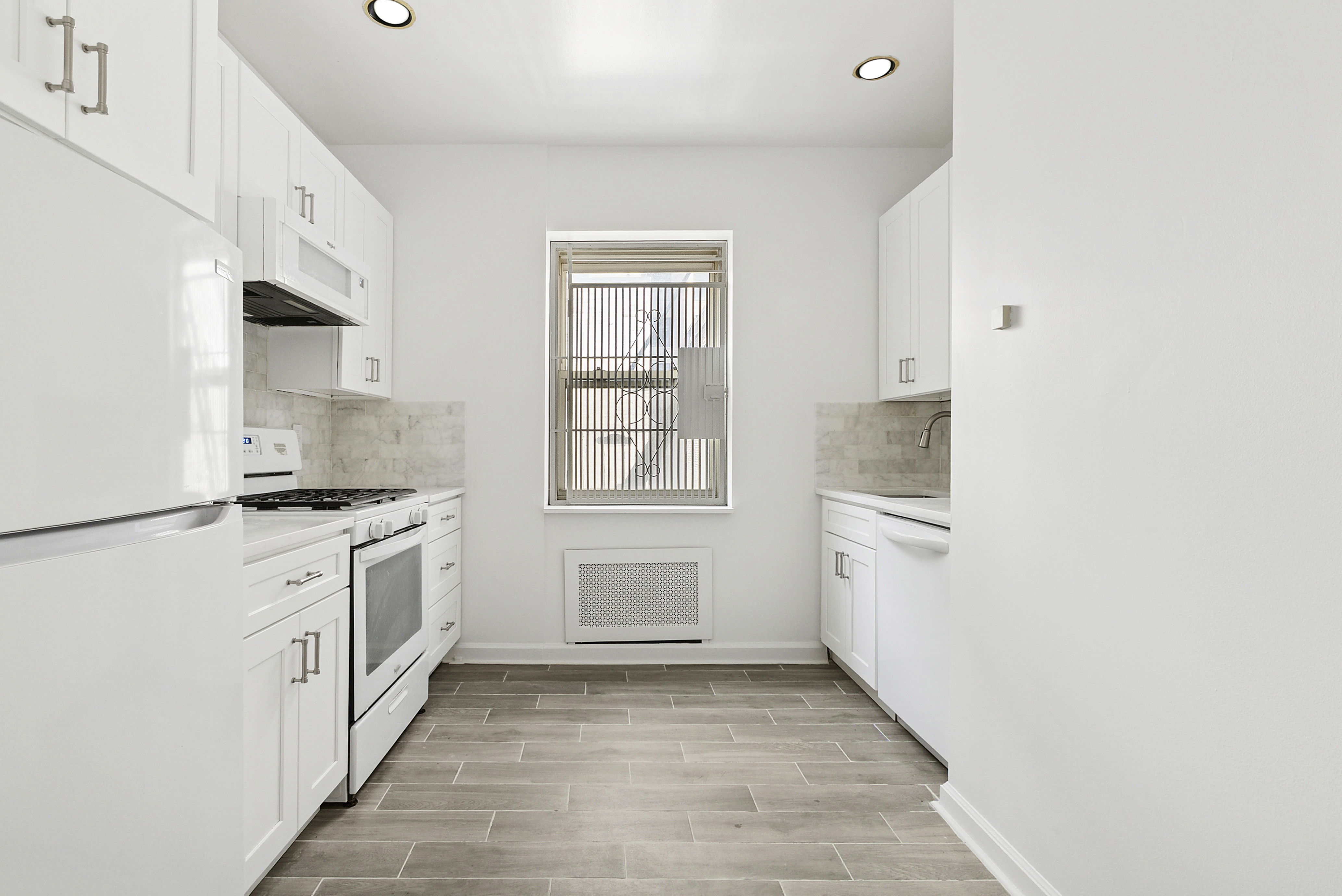 57 West 58th Street, Unit 10E Manhattan, NY 10019 - Photo 3 of 5 a kitchen with white cabinets and white appliances