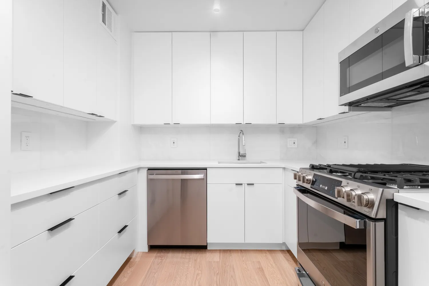 a kitchen with appliances cabinets and a wooden floor