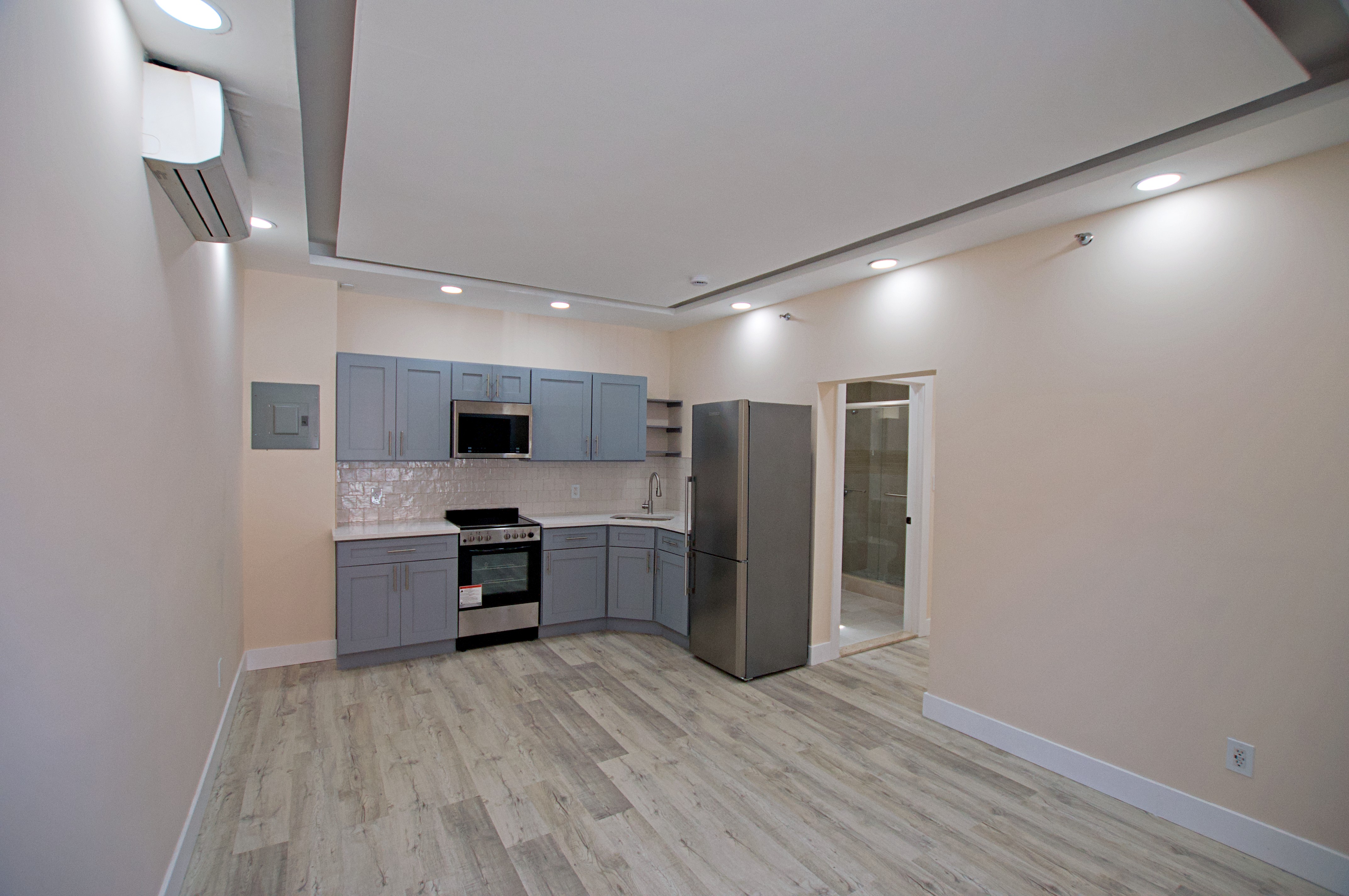 220 Madison Street, Unit 1A Brooklyn, NY 11216 - Photo 4 of 9 an empty room with wooden floor and kitchen view