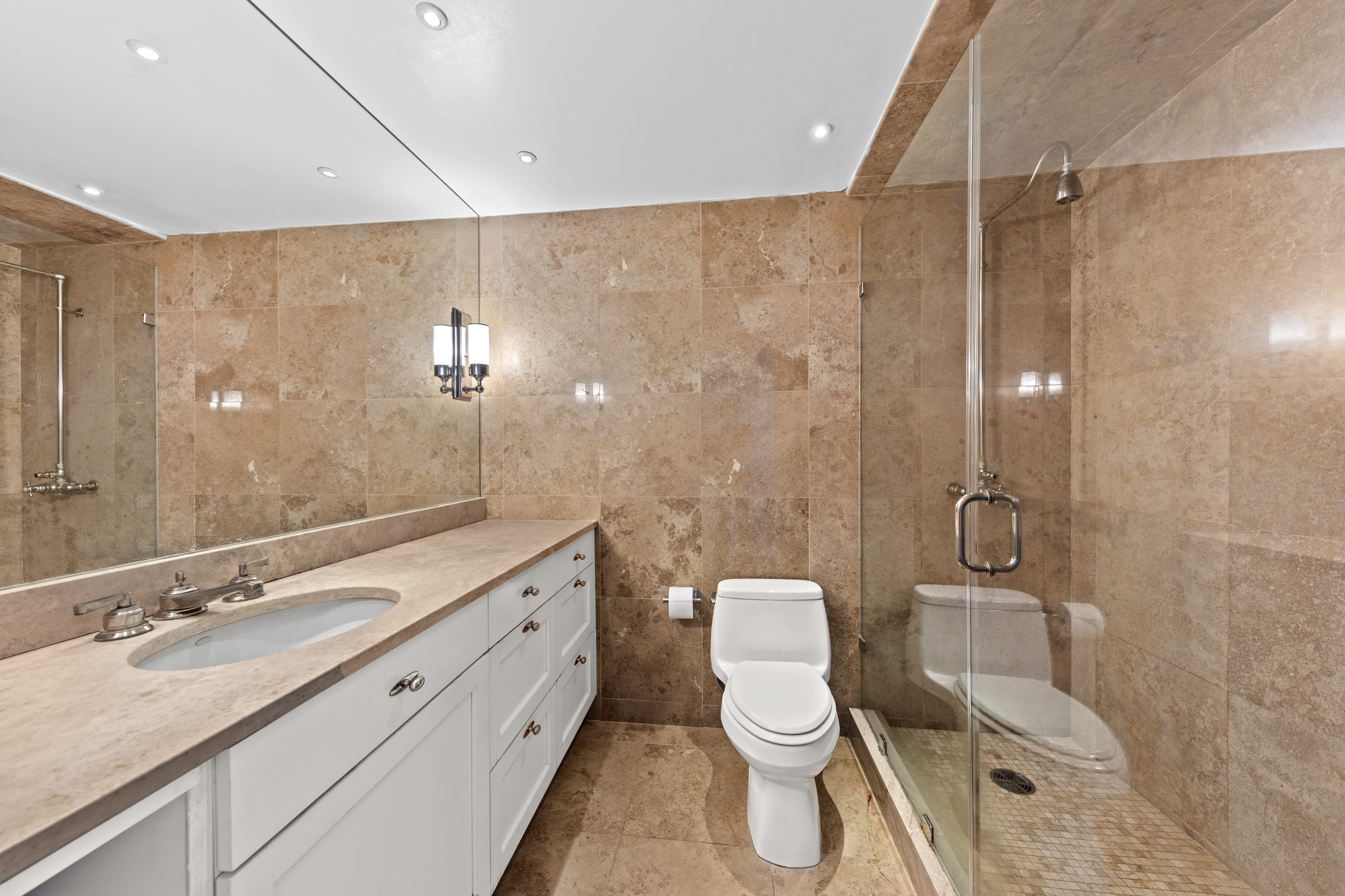 40 East 94th Street, Unit 21F Manhattan, NY 10128 - Photo 4 of 8 a bathroom with a granite countertop sink toilet a mirror and shower