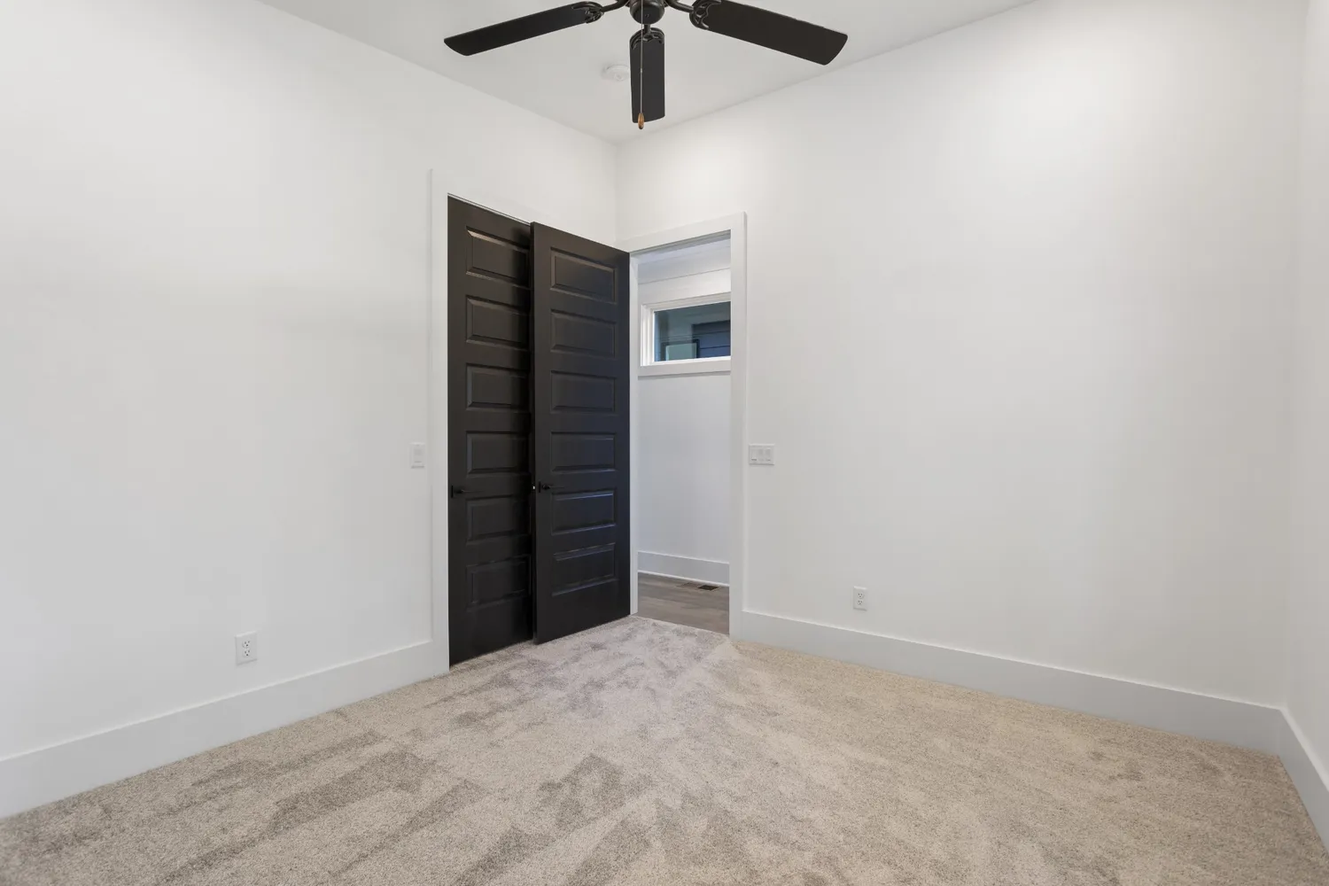 an empty room with wooden floor and a ceiling fan