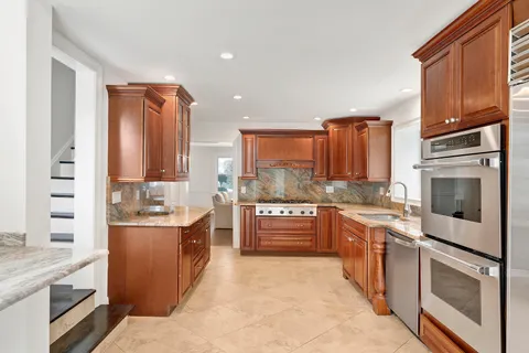 a large kitchen with stainless steel appliances granite countertop a stove a sink and a refrigerator