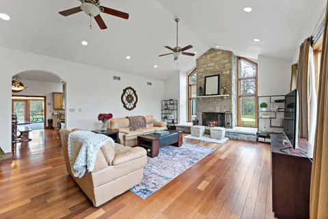 a kitchen with stainless steel appliances kitchen island granite countertop a stove top oven a sink a dining table and chairs with wooden floor