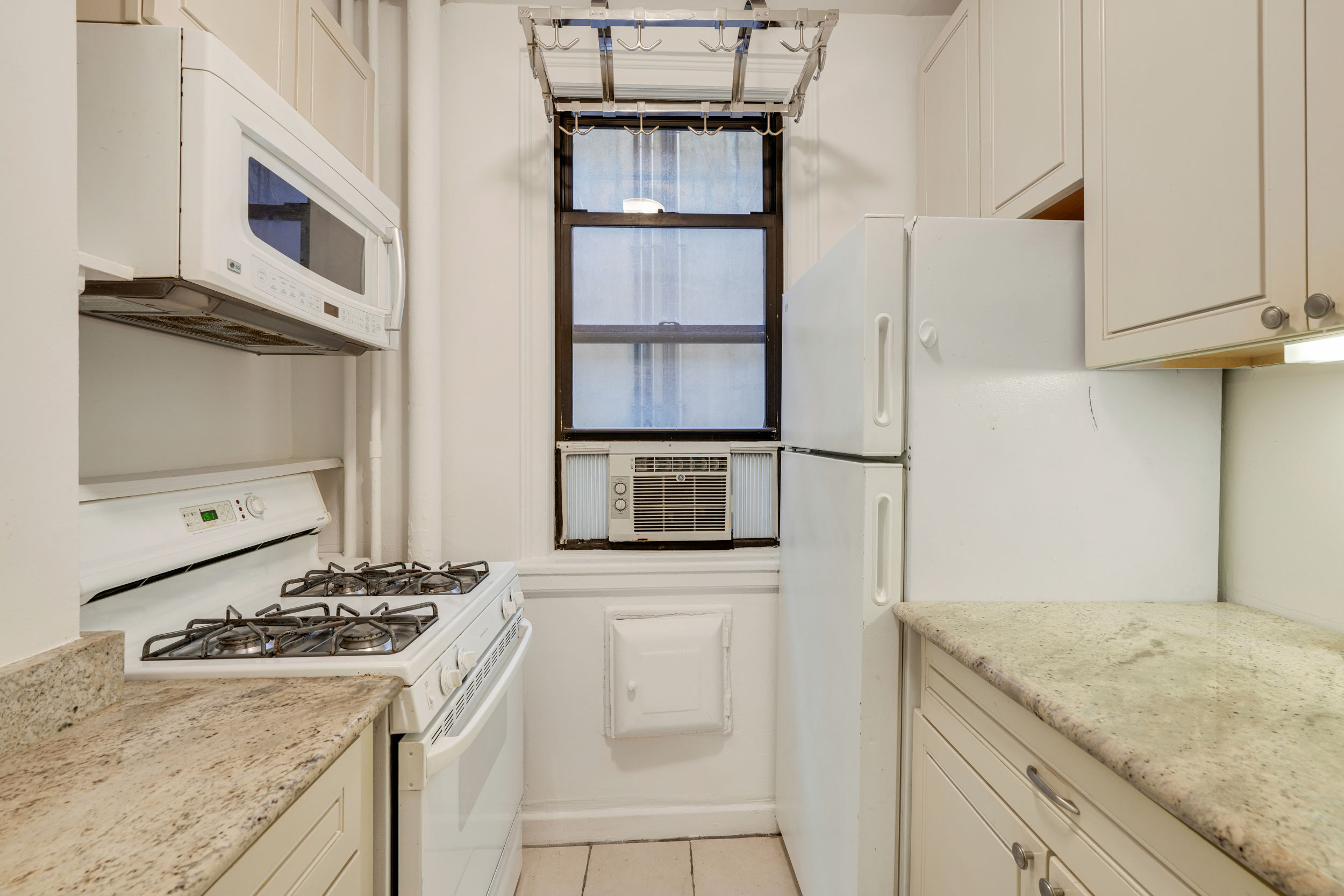 74 West 68th Street, Unit 5A Manhattan, NY 10023 - Photo 7 of 25 a kitchen with stainless steel appliances granite countertop a stove and a microwave
