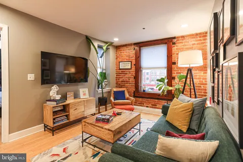 a living room with furniture a flat screen tv and floor to ceiling window
