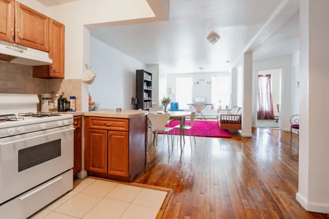 a living room with stainless steel appliances kitchen island granite countertop wooden floors and a view of living room