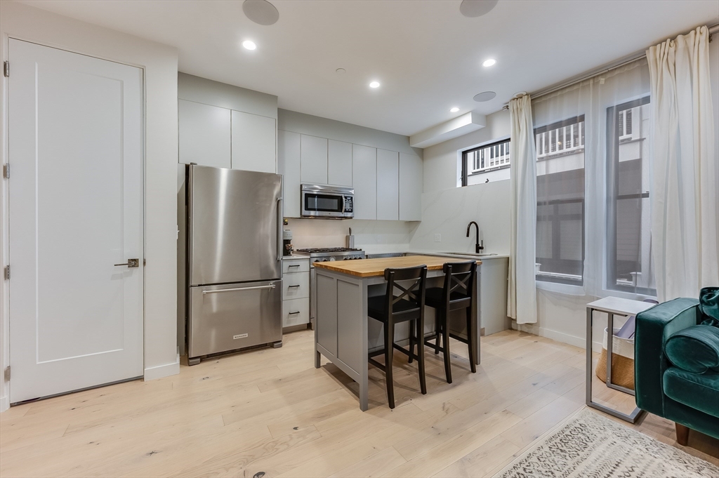 340 West 2nd Street, Unit 5 Boston, MA 02127 - Photo 9 of 26 a kitchen with kitchen island a refrigerator and a stove top oven