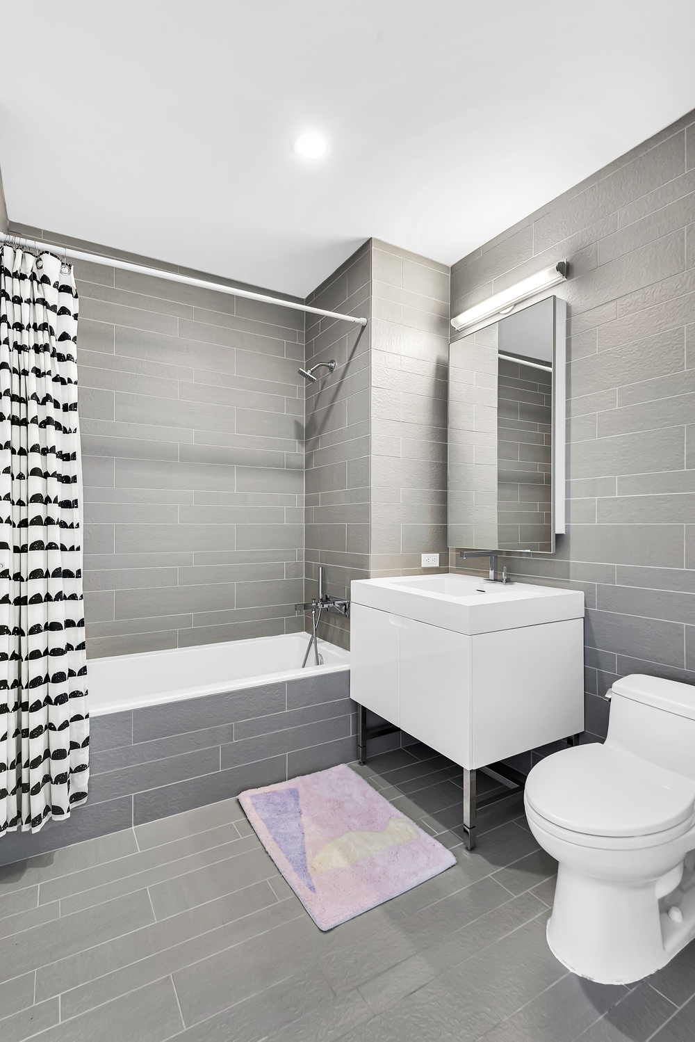 388 Bridge Street, Unit 42G Brooklyn, NY 11201 - Photo 11 of 26 a bathroom with a white tub shower and toilet