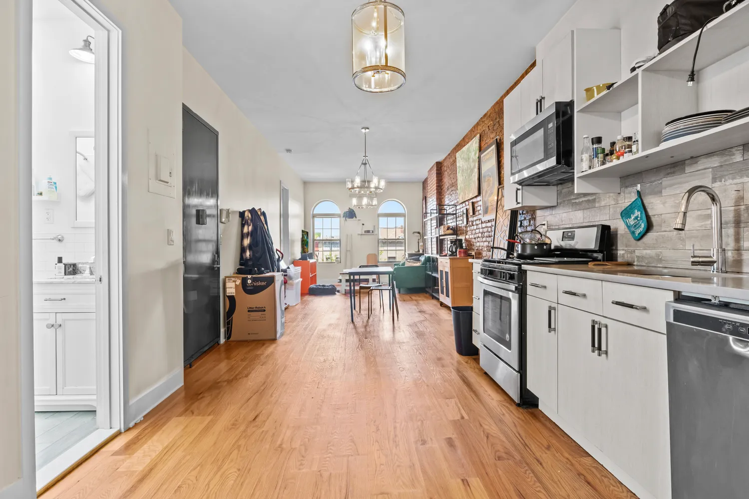 a kitchen with stainless steel appliances granite countertop a refrigerator a stove top oven a sink dishwasher and white cabinets with wooden floor