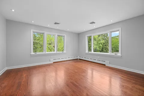 an empty room with wooden floor and windows