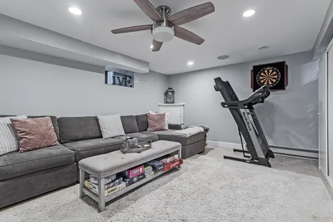 a living room with furniture gym equipment and a ceiling fan