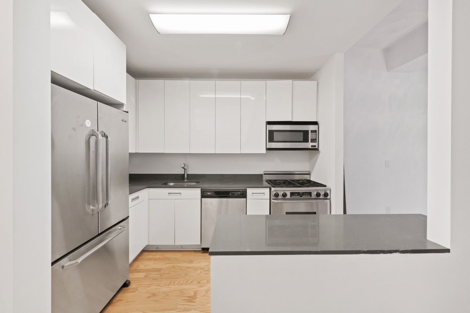 99 John Street, Unit 1711 Manhattan, NY 10038 - Photo 6 of 14 a kitchen with a refrigerator stove and microwave