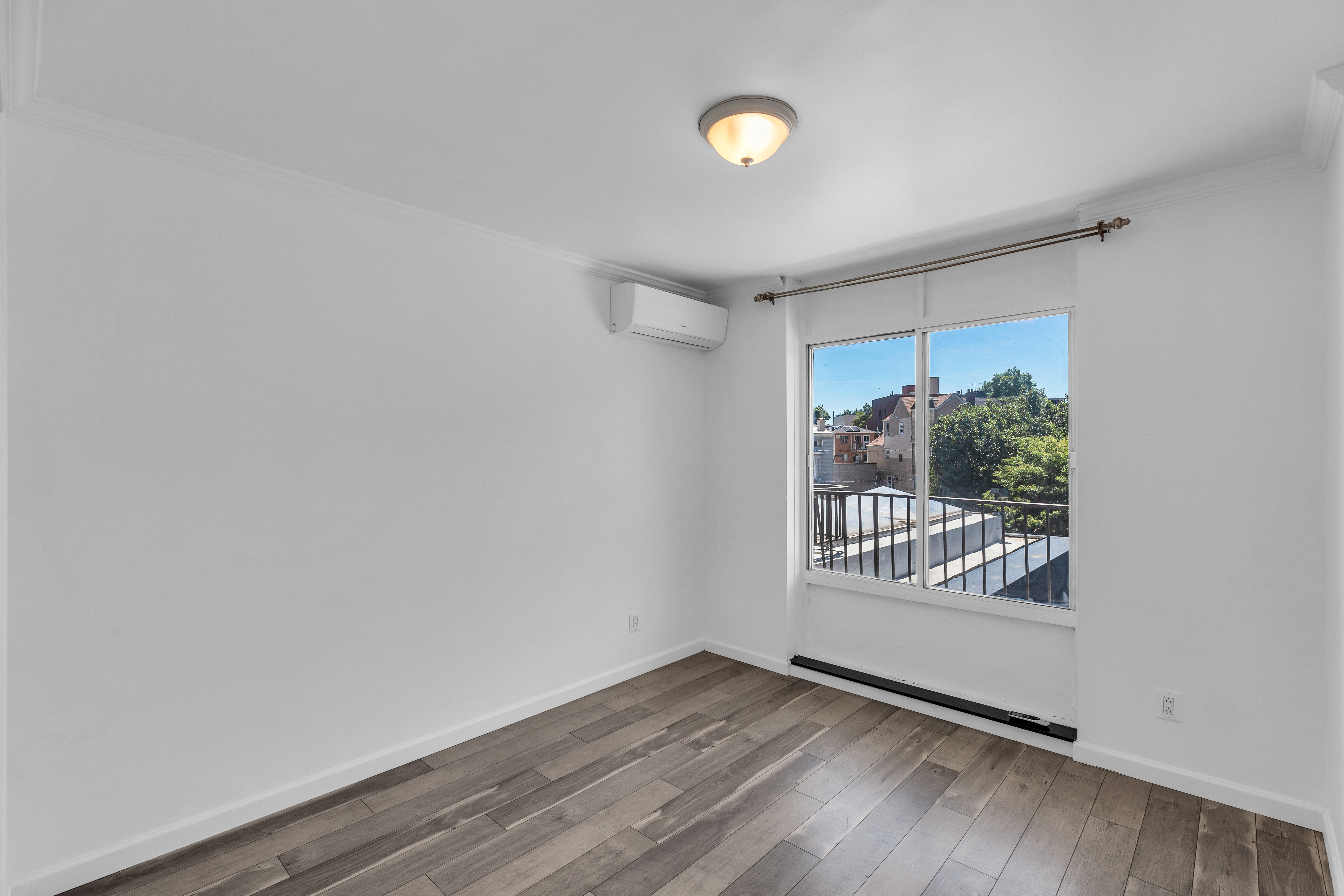 25-40 Shore Boulevard, Unit 2F Queens, NY 11102 - Photo 14 of 31 a view of an empty room with wooden floor and a window