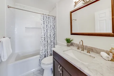 a bathroom with a granite countertop sink toilet and shower