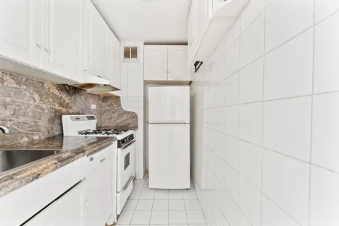 a kitchen with granite countertop white cabinets and white appliances