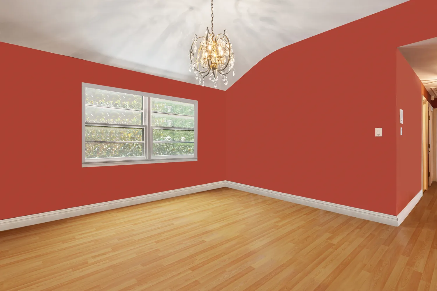 a view of an empty room with window and wooden floor