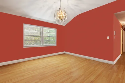 a view of an empty room with window and wooden floor