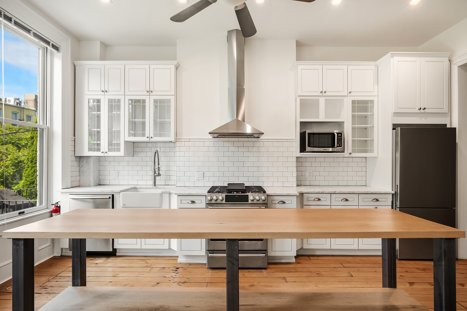a kitchen with stainless steel appliances a table chairs in it and wooden floors