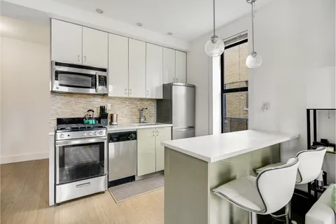 a kitchen with stainless steel appliances white cabinets a sink a stove a refrigerator and island