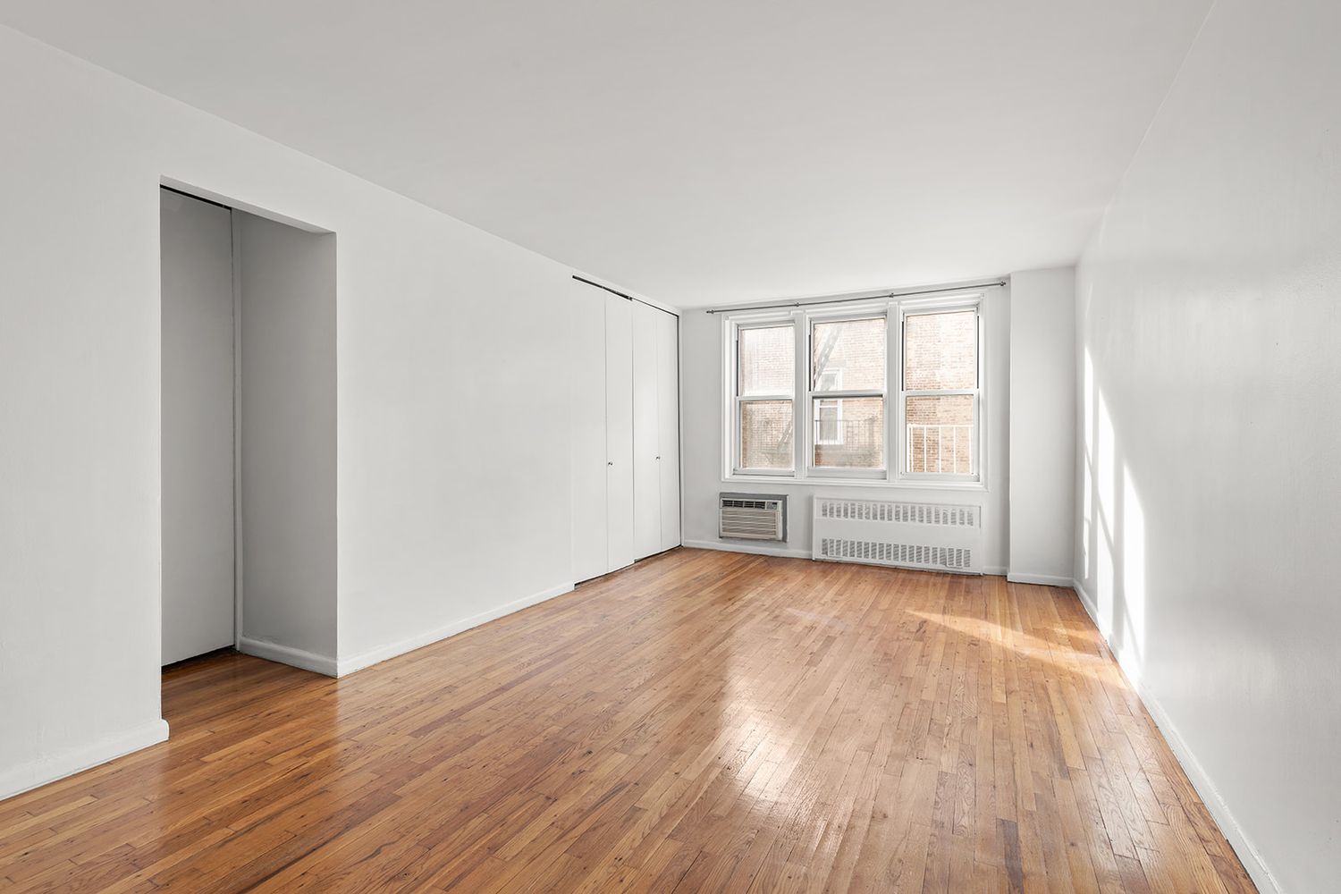 an empty room with wooden floor and windows
