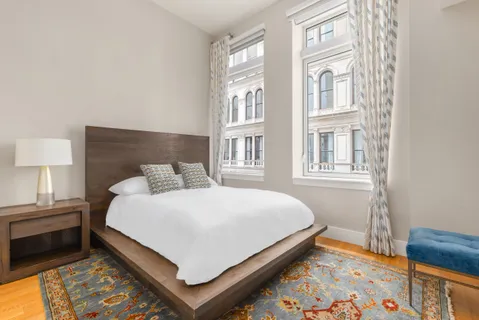 a bed sitting in a bedroom next to a lamp and a dresser