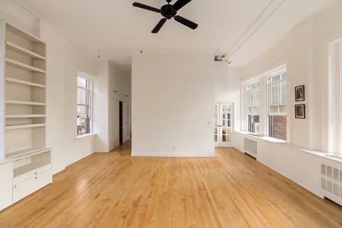 a view of a big room with wooden floor and windows