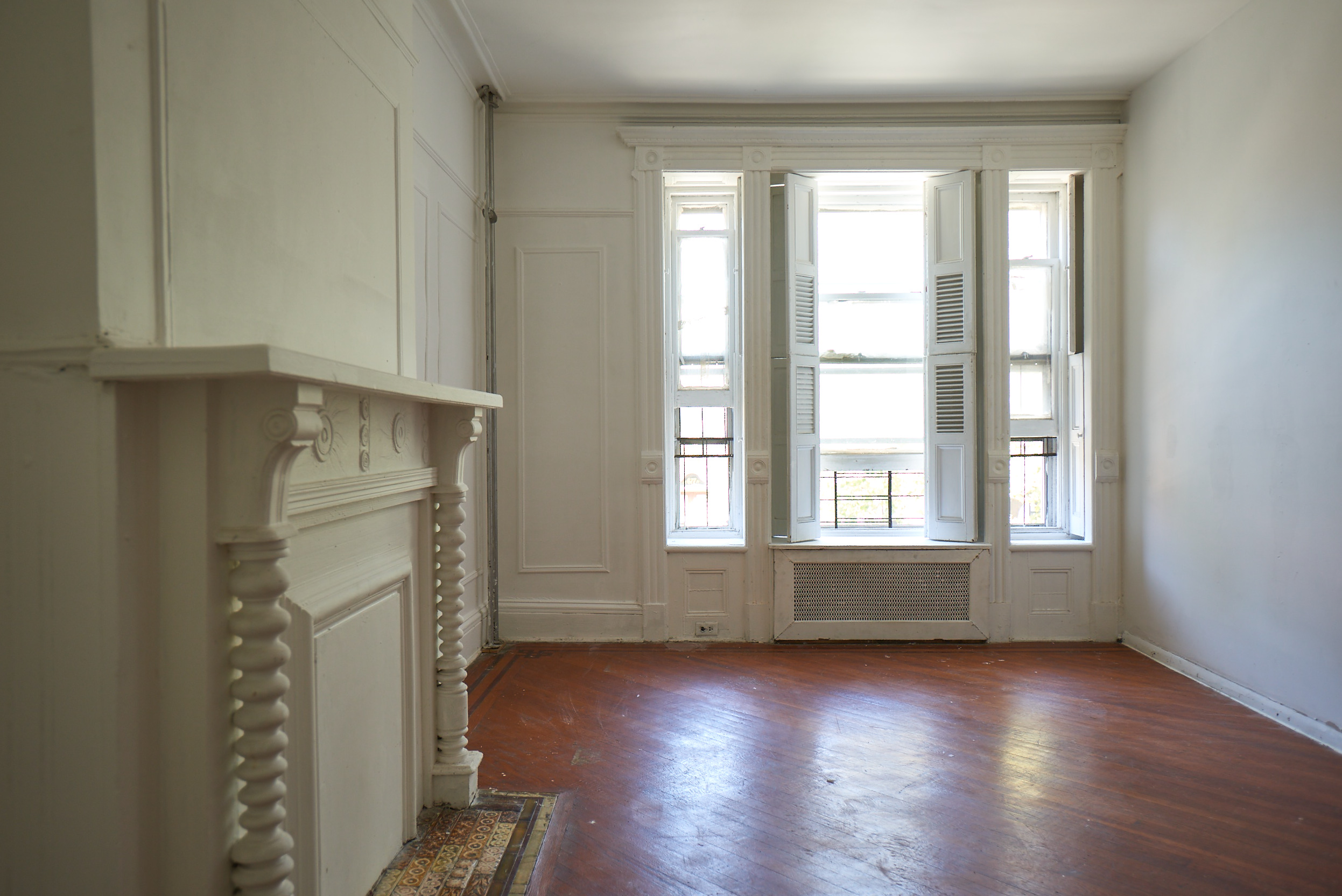 660 Macon Street Brooklyn, NY 11233 - Photo 11 of 17 an empty room with wooden floor and windows with curtains