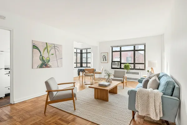 a living room with furniture a rug a lamp and a window