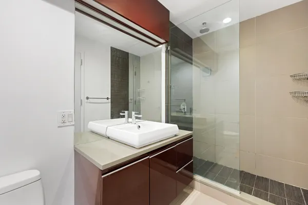 a bathroom with a sink a toilet a mirror and shower