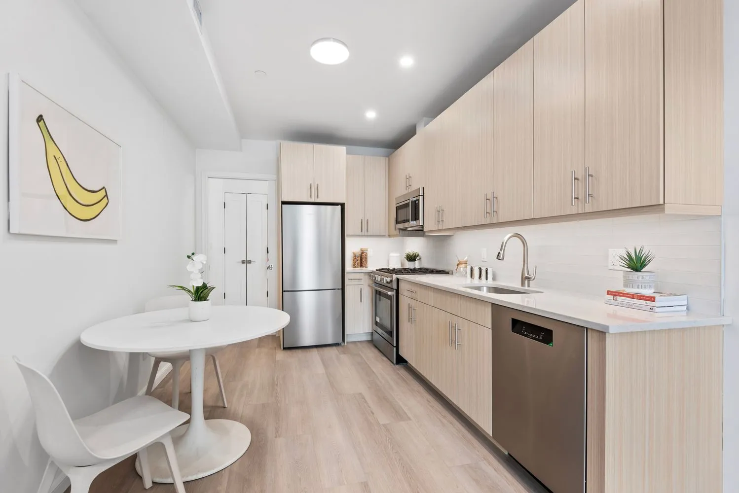 a kitchen with stainless steel appliances granite countertop a sink a stove a refrigerator a dining table and chairs