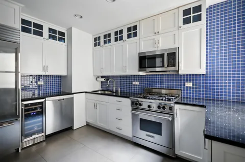 a kitchen with stainless steel appliances white cabinets and stove top oven