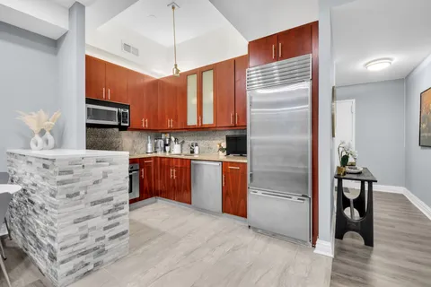 a kitchen with stainless steel appliances kitchen island granite countertop a refrigerator a stove and a wooden floors