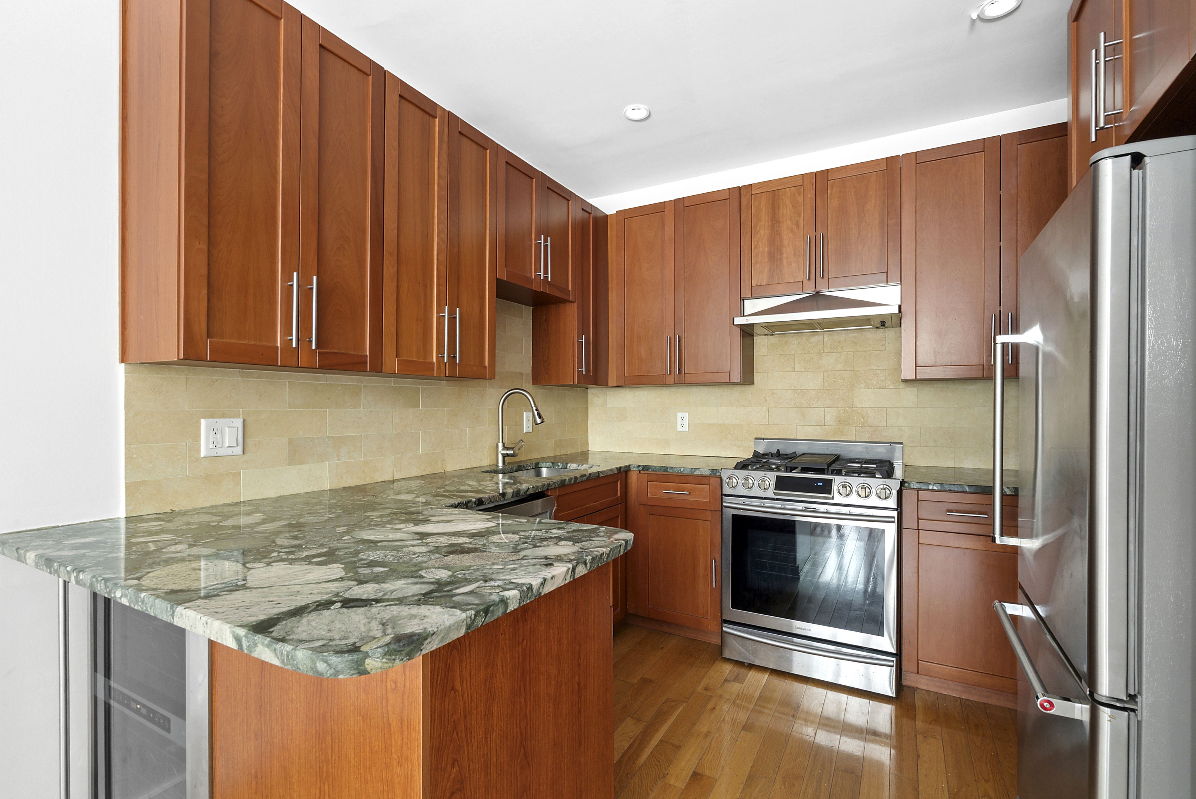 450 East 117th Street, Unit 1A Manhattan, NY 10035 - Photo 3 of 10 a kitchen with granite countertop kitchen island stainless steel appliances a stove refrigerator sink and cabinets