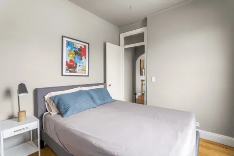 a bedroom with a bed and a painting on the wall