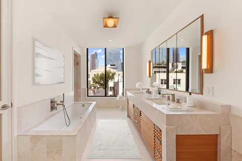 a en suite bathroom with a double vanity sink a mirror and a bathtub