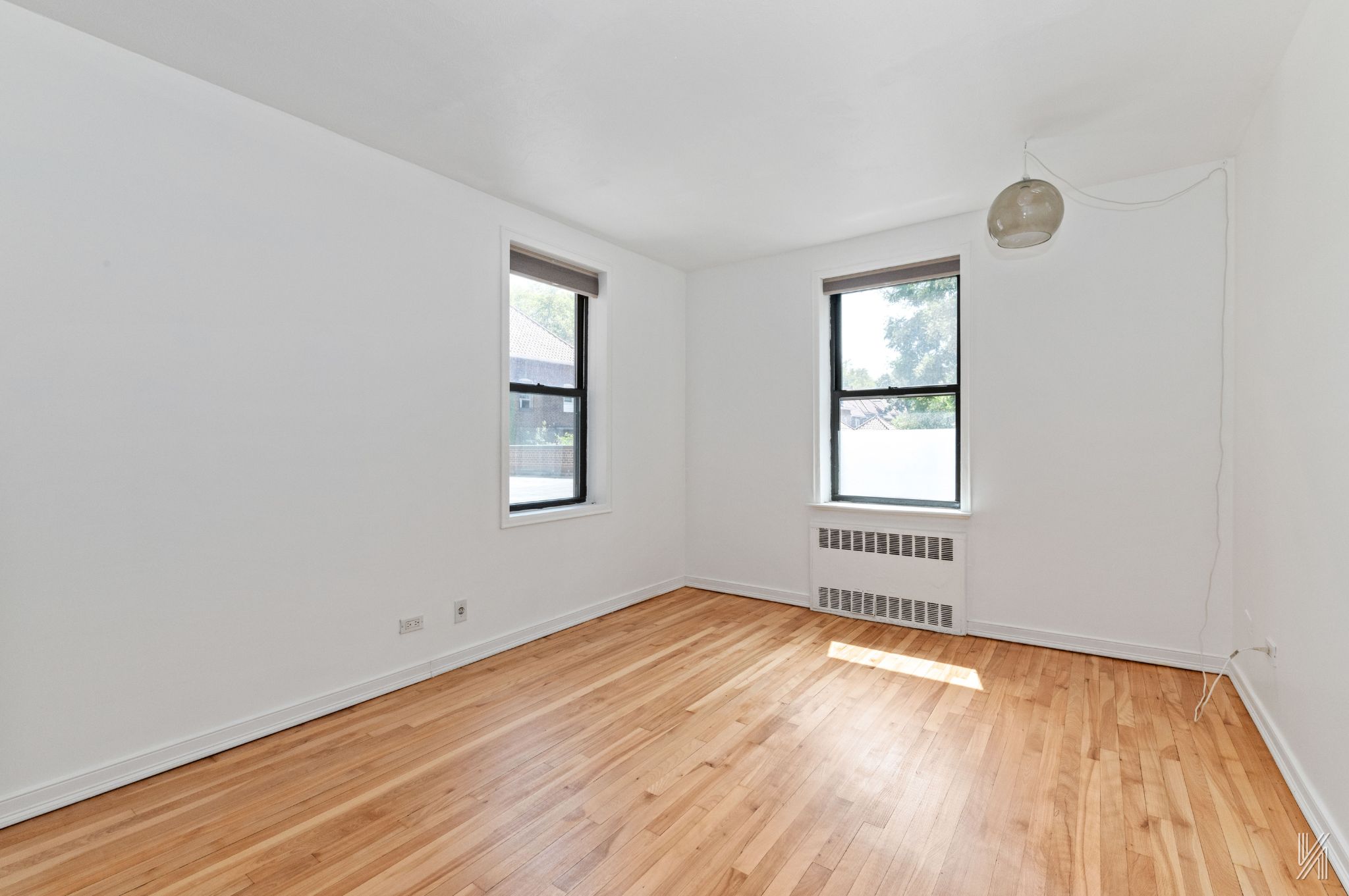 87-10 34th Avenue, Unit 1F Queens, NY 11372 - Photo 4 of 16 an empty room with wooden floor and windows