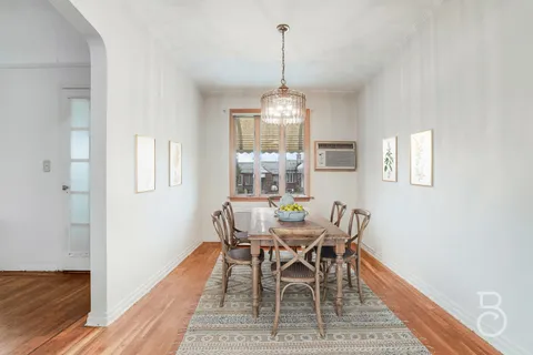 a dining room with wooden floor a chandelier a wooden table and chairs