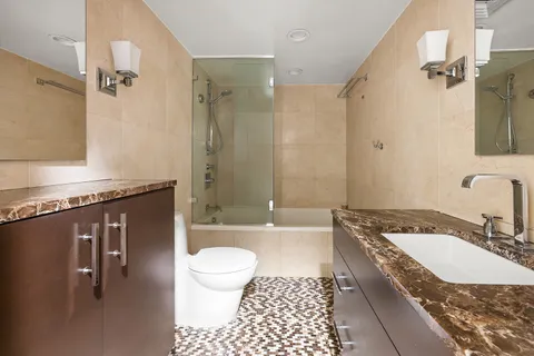 a bathroom with a granite countertop sink a toilet a mirror and shower