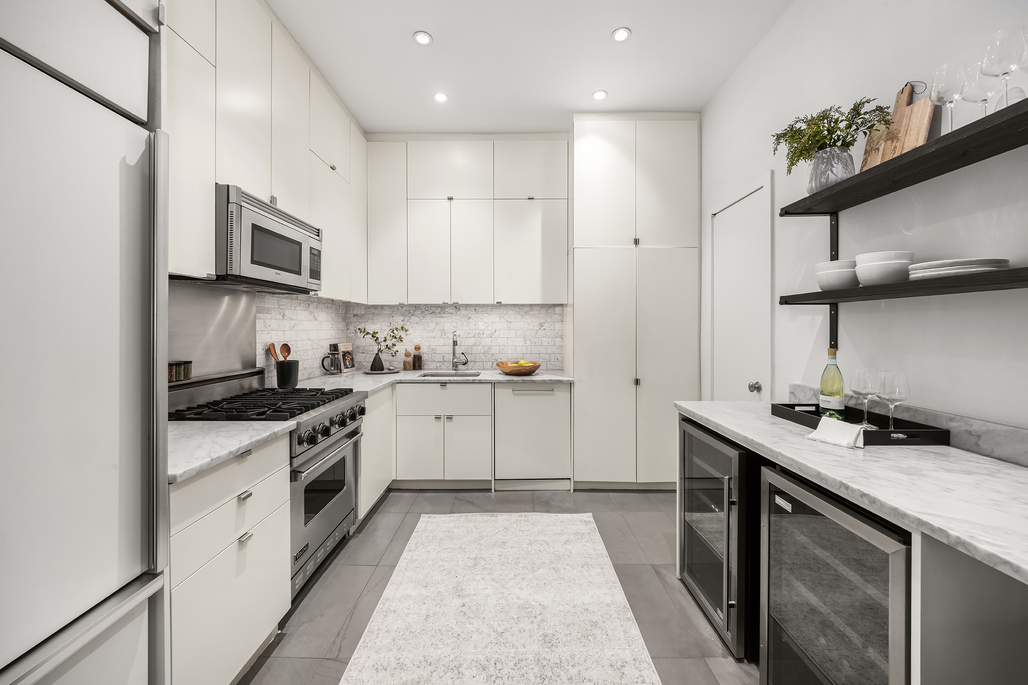 8 Charles Lane, Unit C Manhattan, NY 10014 - Photo 8 of 20 a kitchen with stainless steel appliances granite countertop a sink a stove a microwave and wooden cabinets
