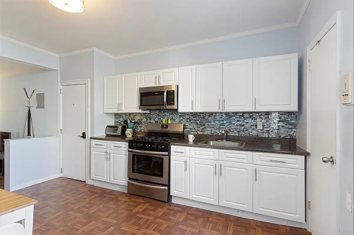 5-39 47th Road, Unit 2R Queens, NY 11101 - Photo 1 of 7 a kitchen with white cabinets and stainless steel appliances