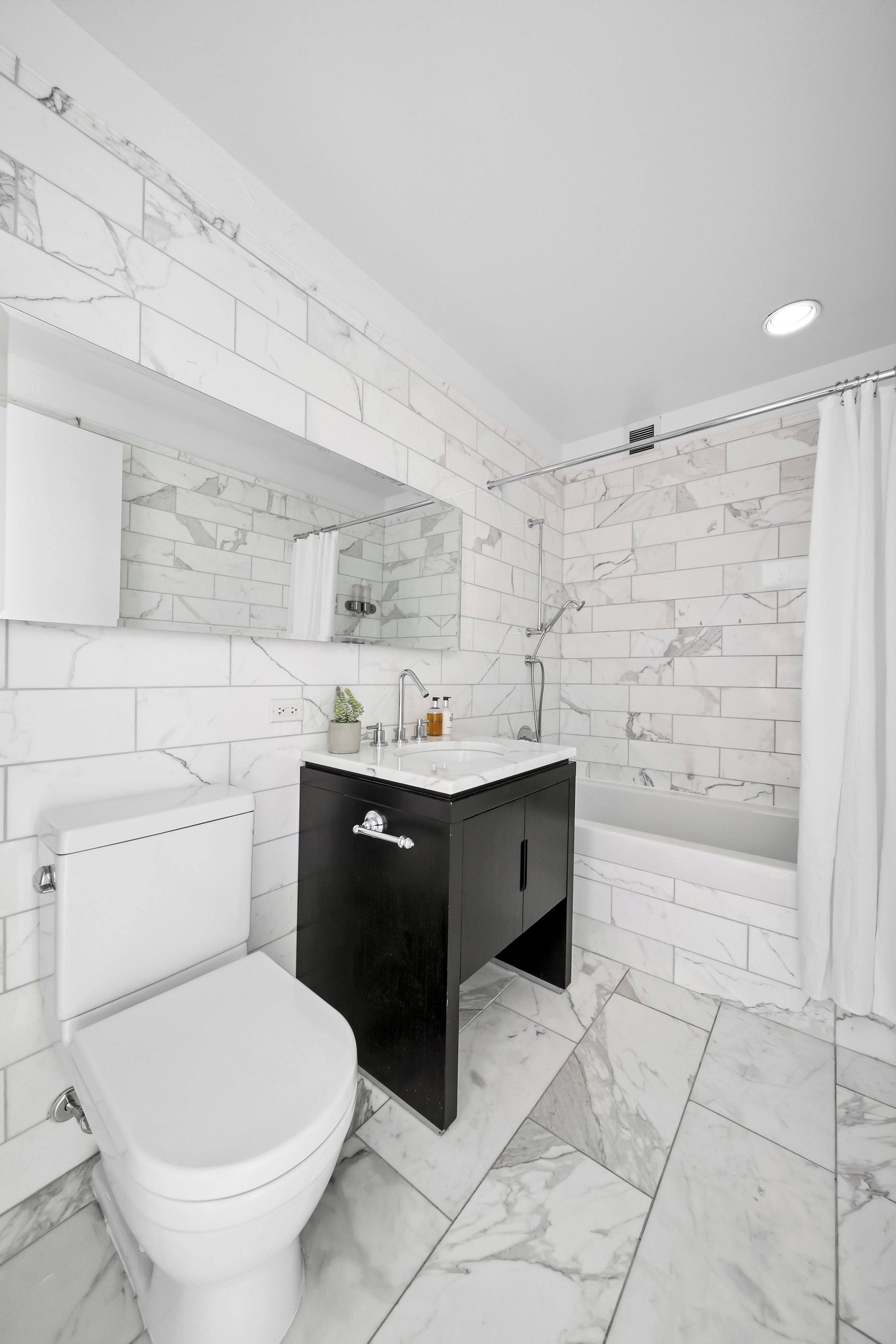 225 5th Avenue, Unit 7K Manhattan, NY 10010 - Photo 12 of 15 a spacious bathroom with a granite countertop toilet a sink a mirror and bathtub