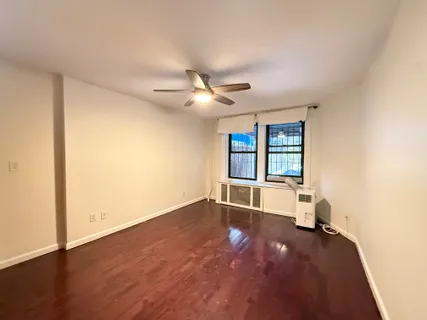 an empty room with ceiling fan and windows