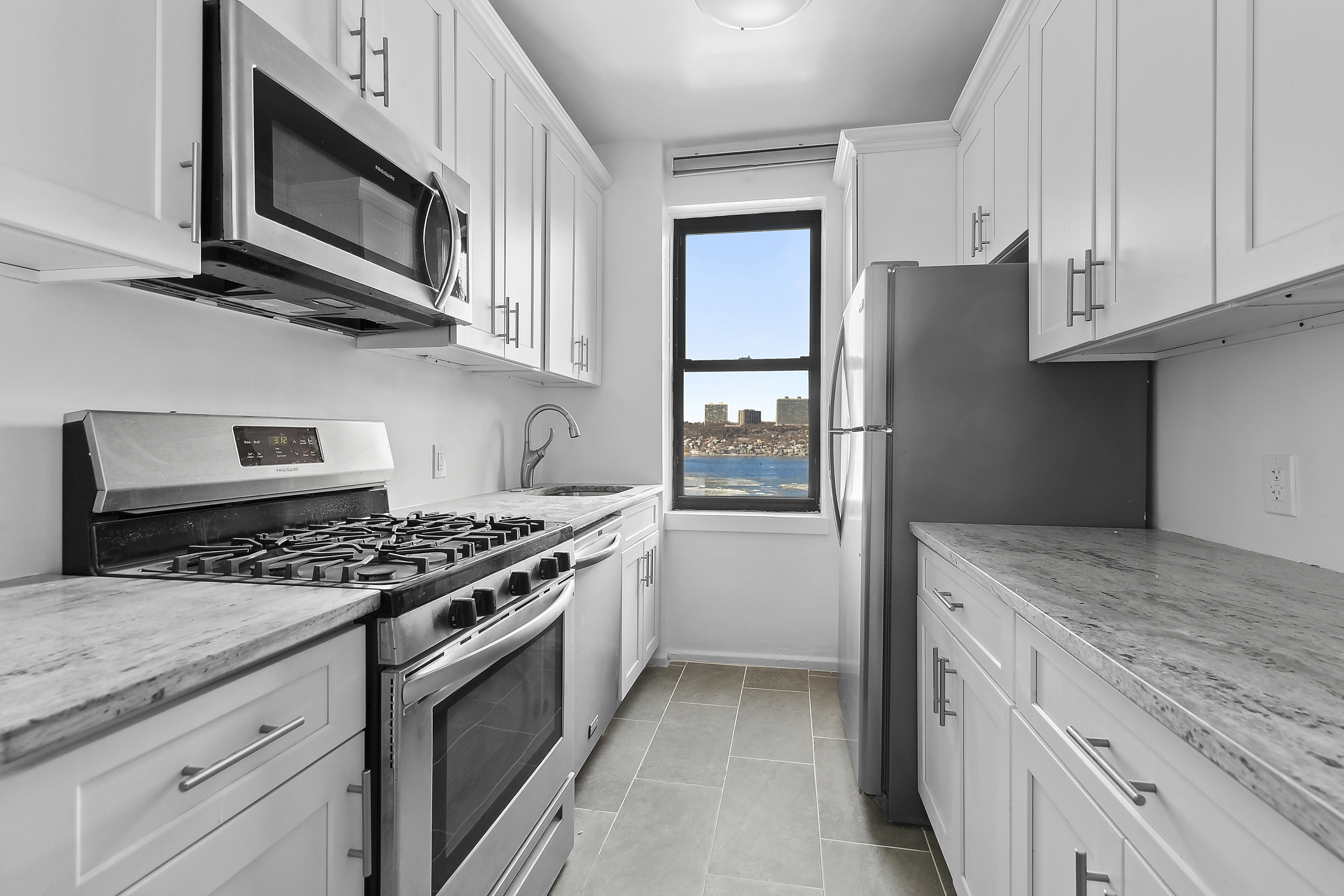 159-34 Riverside Drive West, Unit 5F90 Manhattan, NY 10032 - Photo 6 of 23 a kitchen with stainless steel appliances granite countertop a stove and a microwave