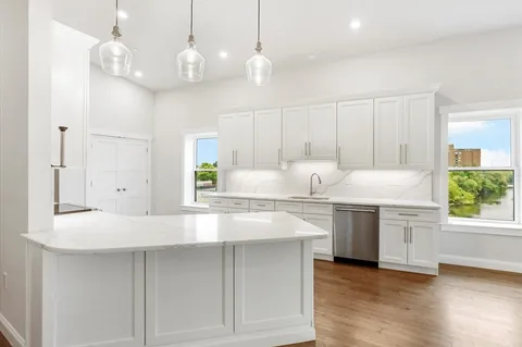 a kitchen with kitchen island granite countertop a sink cabinets and stainless steel appliances