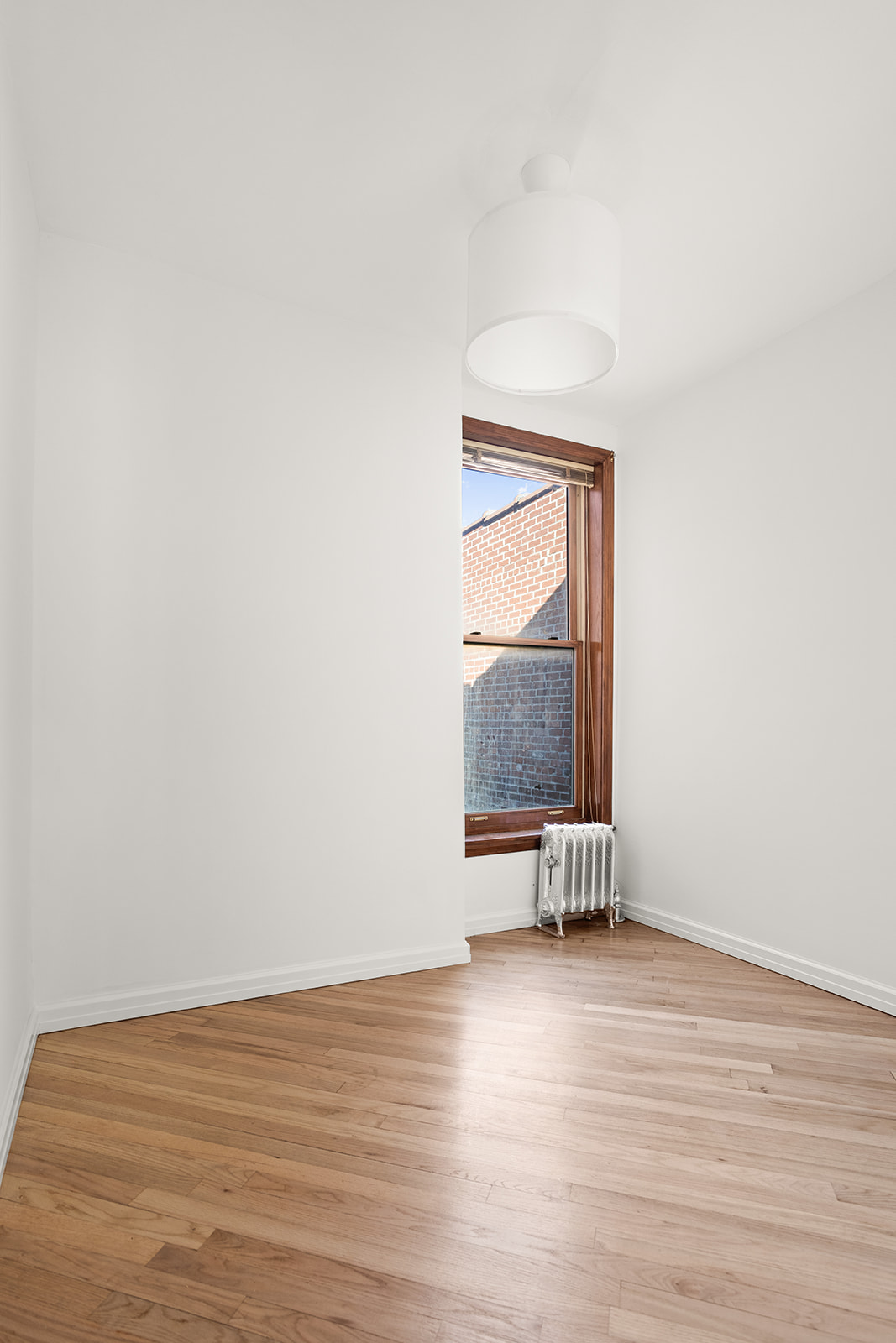 1682 8th Avenue Brooklyn, NY 11215 - Photo 14 of 16 an empty room with wooden floor and windows