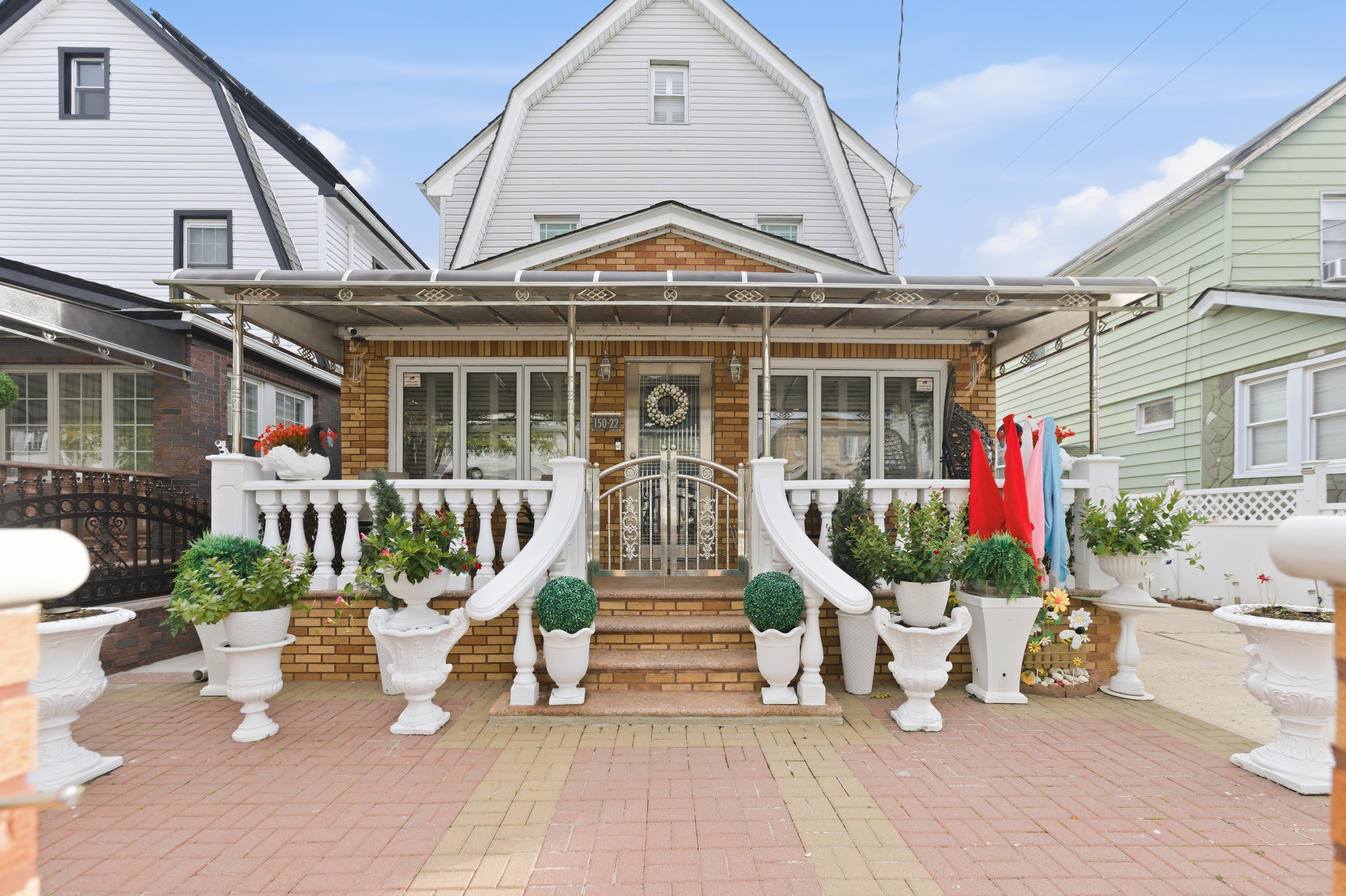150-22 114th Road Queens, NY 11434 - Photo 14 of 22 a front view of a house with a garden and potted plants