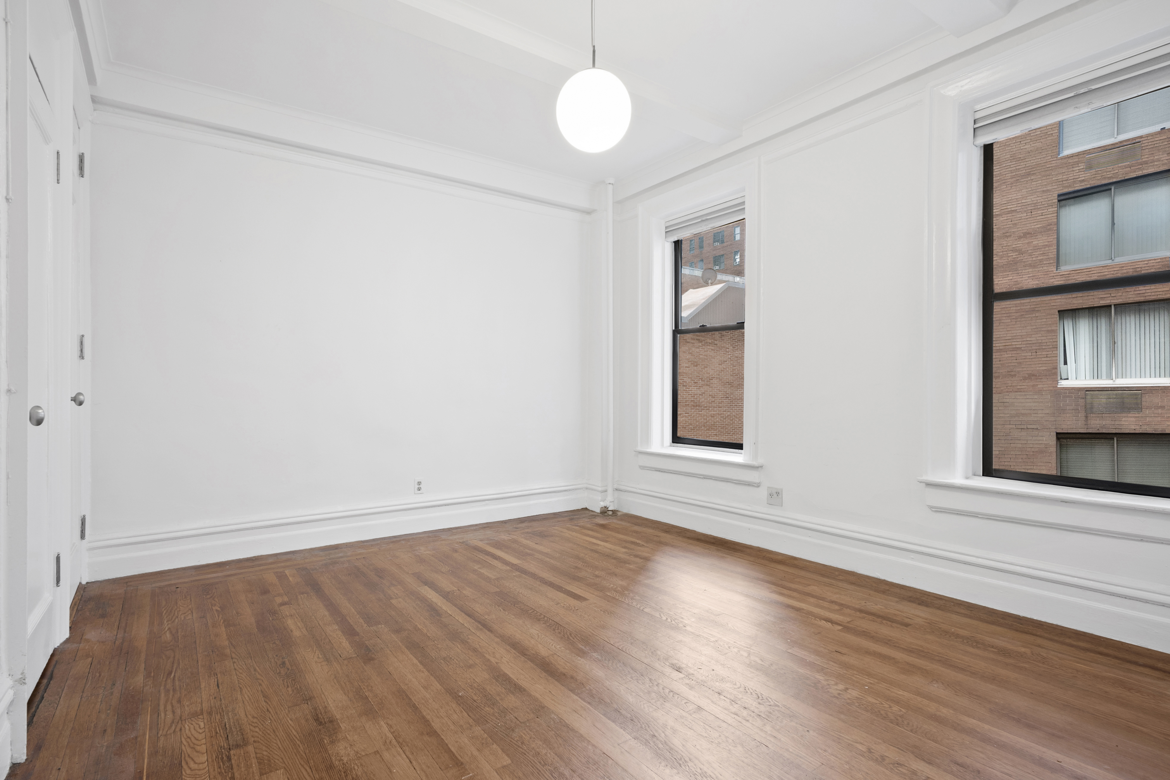 146 East 49th Street, Unit 6CD Manhattan, NY 10017 - Photo 7 of 12 an empty room with wooden floor chandelier fan and windows