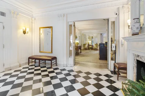 a living room with a black white checkered floor with a gaming machine and dining chair